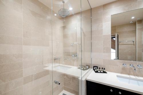 a bathroom with a sink and a glass shower at Hôtel Le Presbytère in Paris