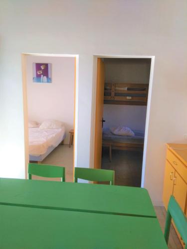 a room with a green table and chairs and a bedroom at Village Vacances Yaloer in Villefranche-de-Panat