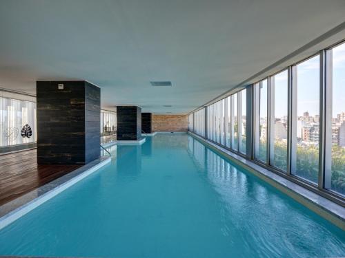 a large swimming pool in a building with windows at Quartier Hollywood by RentinBA in Buenos Aires