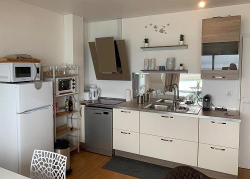 a kitchen with a white refrigerator and a sink at UN BALCON SUR LA MER, ACCES DIRECT A LA PLAGE in Granville