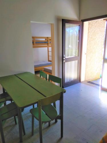 a dining room with a green table and chairs at Village Vacances Yaloer in Villefranche-de-Panat