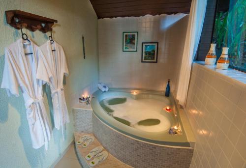 um banheiro com banheira no canto de um cômodo em POUSADA NICO ON THE HILL em Monte Verde