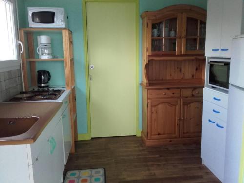 - une cuisine avec des murs verts et un réfrigérateur blanc dans l'établissement Au calme, les pieds dans l'eau, 106 Route de la Pointe de Ruault 56370 SARZEAU, à Sarzeau