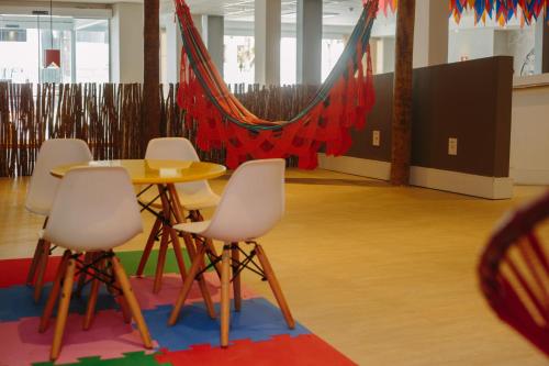 a table and chairs in a room with a hammock at ibis Styles Campina Grande in Campina Grande
