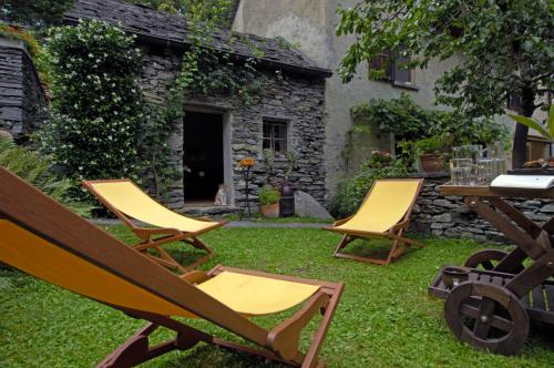 2 chaises et une table dans la cour dans l'établissement Pensione Boschetto, à Cevio