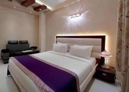 1 dormitorio con 1 cama blanca grande y 1 silla en Hotel Central Residency, en Varanasi