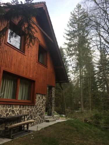 a wooden house with a bench in front of it at Chata VYPO in Liptovský Ján