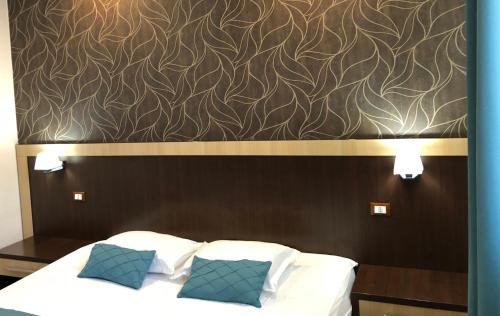 a bed with two pillows and a brown wall at Pensiunea Lido in Piatra Neamţ