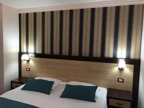 a bedroom with a large bed with two blue pillows at Pensiunea Lido in Piatra Neamţ