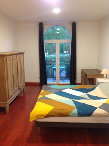 une chambre avec un lit et une grande fenêtre dans l'établissement L'Apogée, à Thoirette