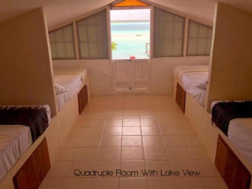 a room with three beds and a window with the ocean at Hotel CasaBakal - A pie de Laguna - Bacalar in Bacalar