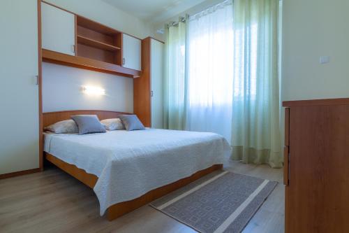 a bedroom with a bed and a large window at Apartments & Rooms Sanja in Rab