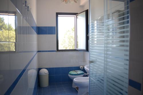 ein blau-weißes Bad mit einem WC und einem Fenster in der Unterkunft Santanna Beach House - Fondachello-apartments com in Mascali