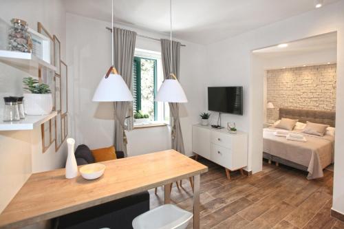 uma pequena sala de estar com uma cama e uma mesa em Apartments Tessera em Split