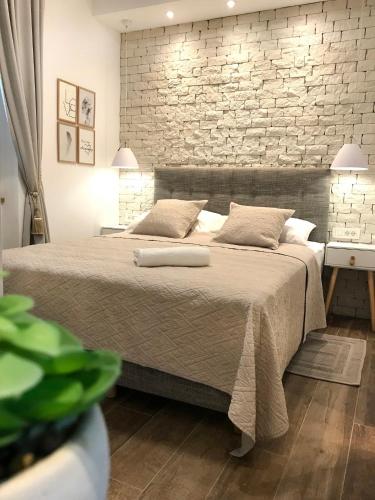 a bedroom with a large bed with a brick wall at Apartments Tessera in Split