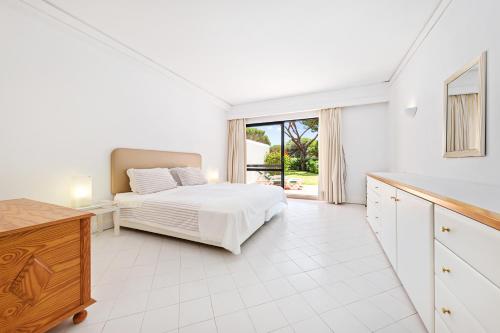 a white bedroom with a bed and a large window at Victory Village 10D in Quinta do Lago
