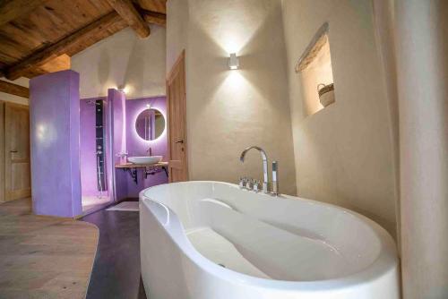 una grande vasca bianca in un bagno con pareti viola di Tenuta Armonia a Clavesana