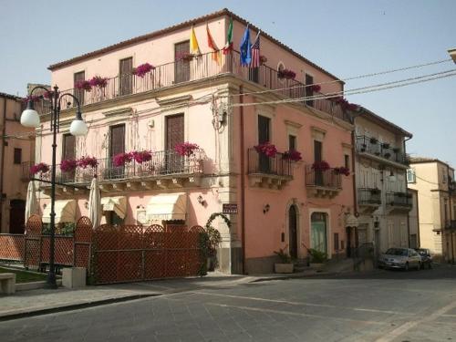 un edificio rosa con banderas y flores en los balcones en Il Rustico, en Grammichele