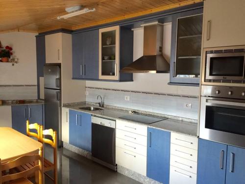 una cocina con armarios azules y blancos y una mesa. en Apart. cerca de Playa Catedrales en Lourenzá