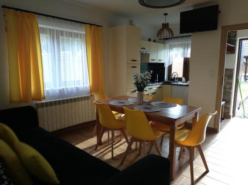 a kitchen and dining room with a wooden table and yellow chairs at Słoneczna Polana in Solina