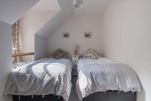 two beds in a room with white walls at The Blue Hoose in Gardenstown