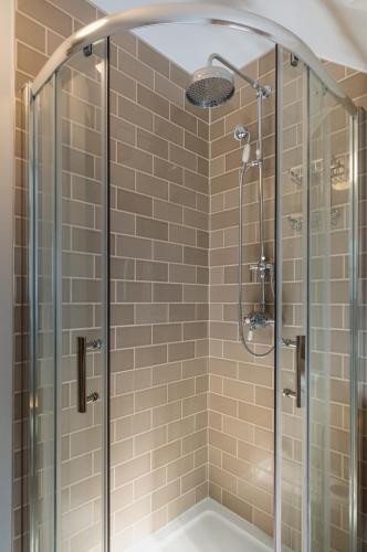 a shower with a glass door and a shower head at The Blue Hoose in Gardenstown