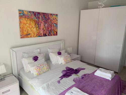 een slaapkamer met een wit bed met paarse bloemen erop bij Urban Apartment in Petrovac na Moru