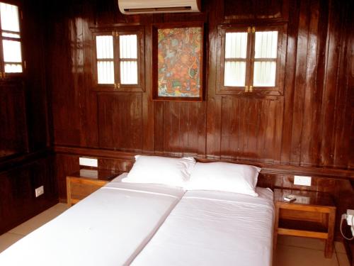 Cama en habitación con paredes y ventanas de madera en Omsam Guest Home, en Varkala