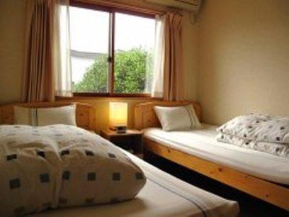 a bedroom with two beds and a window at Guesthouse Mintaro Hut in Yamagata