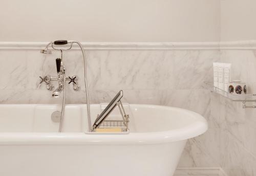 a white bath tub with a shower in a bathroom at Rosewood Miramar Beach in Santa Barbara