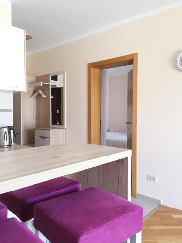 a kitchen with purple stools in front of a counter at Lila apartmani in Baošići