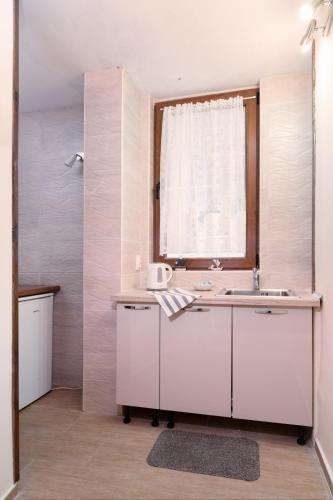 a white kitchen with a sink and a window at Sozopol Seaside Apartment in Sozopol