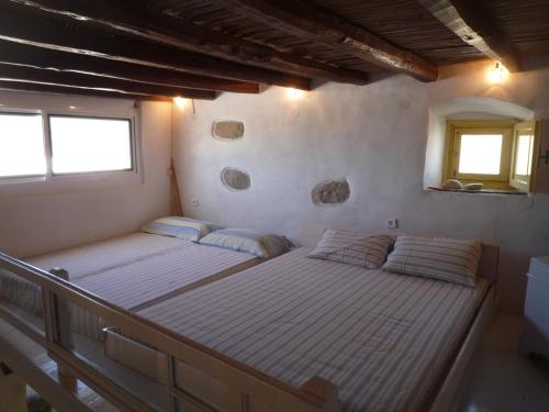 two beds in a room with two windows at Open Space House at the Castle of Chora, Serifos in Serifos Chora