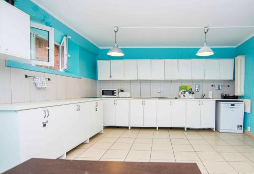 a large kitchen with white cabinets and blue walls at Student-House Kazimierzowska in Warsaw