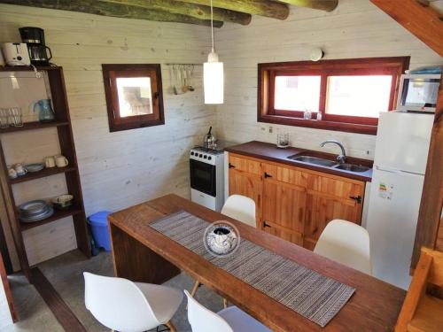 a small kitchen with a table and a refrigerator at Casas Sadhana in Punta Del Diablo