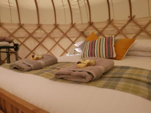 a bed with towels and two teddy bears on it at Syke Farm Campsite - Yurt's in Buttermere