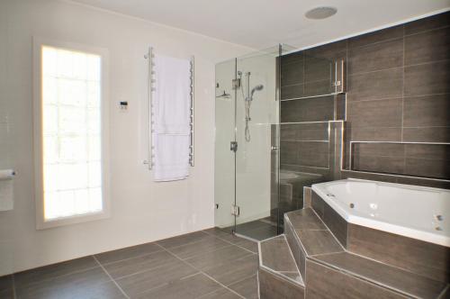 Das Bad ist mit einer Badewanne und einer Dusche ausgestattet. in der Unterkunft LUXURIOUS Couples Escape, SPA BATH, Netflix, NBN in Victor Harbor