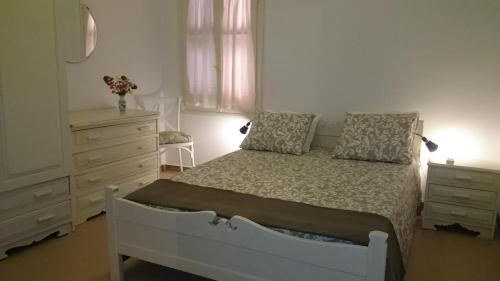 a bedroom with a white bed and a dresser at Casa Patrikò Chania in Perivólia