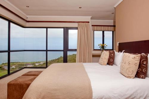 a bedroom with a large bed and large windows at Hippo House in Knysna