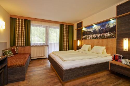 a bedroom with a large bed and a chair at Hotel Gundolf in Sankt Leonhard im Pitztal