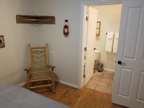 ein Schlafzimmer mit einem Bett und einem Stuhl sowie ein Badezimmer in der Unterkunft Roche Bonhomme Rustic Suite in Jasper