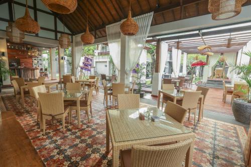 a restaurant with tables and chairs and windows at Argya Santi Resort in Jimbaran