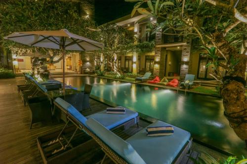 a swimming pool with lounge chairs and an umbrella at Argya Santi Resort in Jimbaran