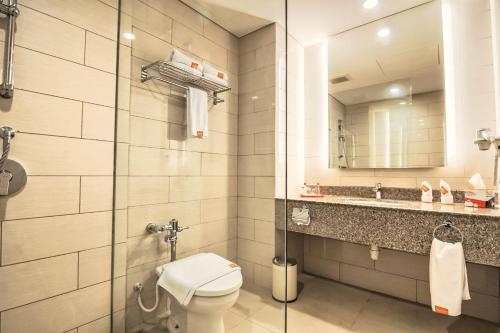 a bathroom with a toilet and a sink and a mirror at HARRIS Resort Batam Waterfront in Sekupang