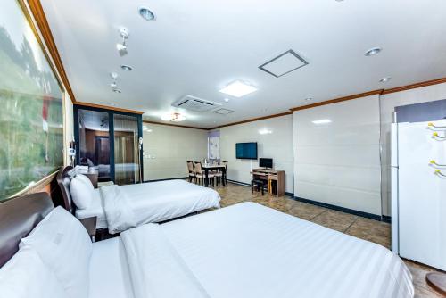 a hotel room with two beds and a desk at Tamragio Residence Hotel in Jeju