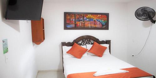 1 dormitorio con 1 cama con almohadas de color naranja y una pintura en Hotel el imperio en Quibdó