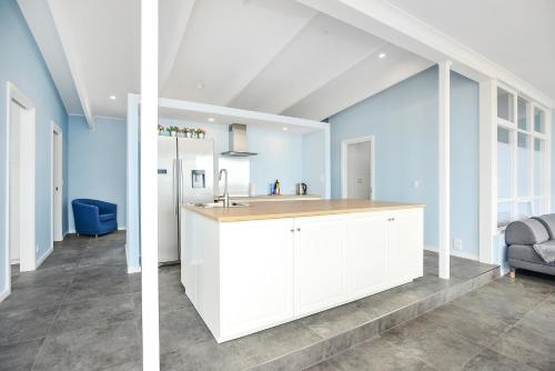 a kitchen with white cabinets and a blue wall at Salomon Sea Haus - Sellicks Beach - C21 SouthCoast Holidays in Sellicks Beach