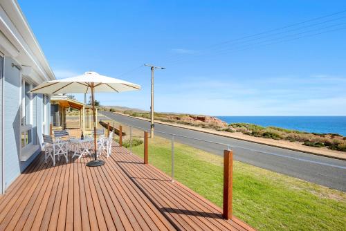 a porch with an umbrella and chairs and the ocean at Salomon Sea Haus - Sellicks Beach - C21 SouthCoast Holidays in Sellicks Beach