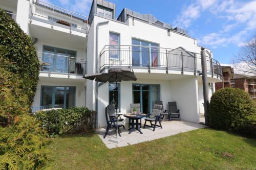 une maison blanche avec une table, des chaises et un parasol dans l'établissement Residenz Bellevue exklusive Fewo 39, à Zinnowitz