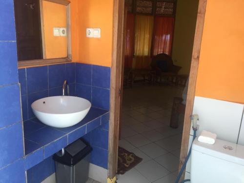 a bathroom with a bowl sink on a blue tiled wall at Oro Beach Houses in Weetebula